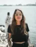 woman in black crew neck t-shirt wearing brown framed eyeglasses standing on rocky shore during